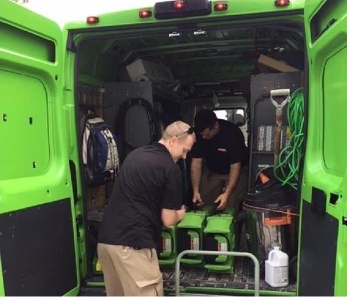 photo of two technicians loading a servpro truck with equipment.